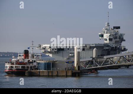 The mersey ferry Royal Iris dwarfed by the Royal Navy's new aircraft carrier HMS Prince of Wales moored at Pier Head, Liverpool