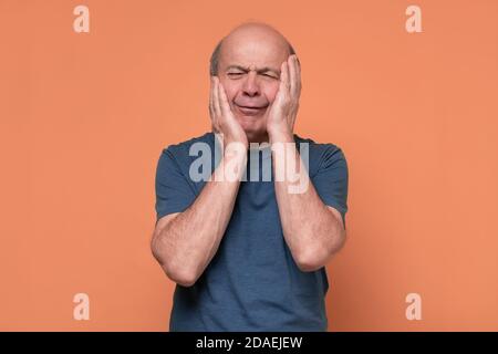 Senior man holding his cheek with hand, suffering from bad toothache. Stock Photo