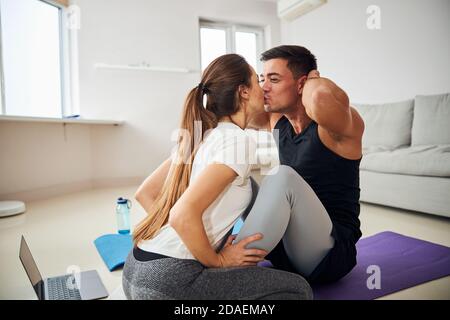 Young brunette man getting kisses from girlfriend for doing sit-ups Stock Photo