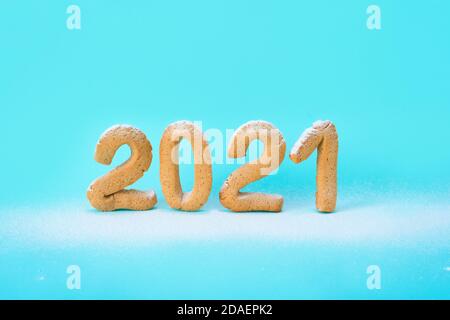 number 2021 of ginger cookies is sprinkled with powdered sugar on a blue background . festive new year background, template for greeting cards. concep Stock Photo