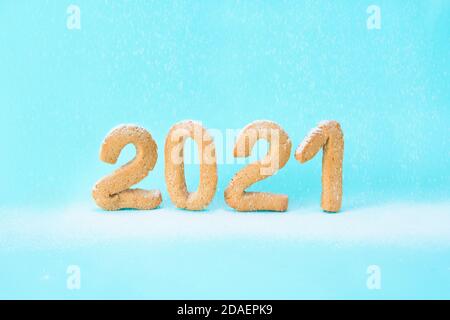 number 2021 of ginger cookies is sprinkled with powdered sugar on a blue background . festive new year background, template for greeting cards. concep Stock Photo