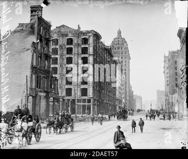 View of pedestrians and horse-drawn vehicle traffic moving along Market Street in San Francisco, California, past ruins after the 1906 earthquake. Stock Photo