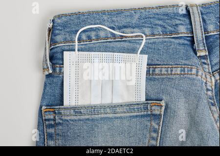 Clean face mask in back blue jeans pocket close up view Stock Photo