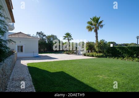 Driveway and front garden of a luxury villa with green lawn and calcada style paving Stock Photo