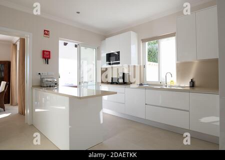 Brand new modern kitchen with white cabinets and beige stone counter top and ceramic tiled floor Stock Photo