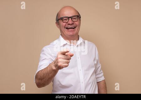 Handsome senior man laughing at you, pointing finger to the camera Stock Photo