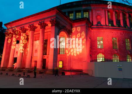 Armistice Day Commemoration during lockdown. Manchester Central Library exterior, UK lit with red light and poppy design. St Peter's Square Stock Photo