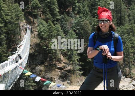 Portrait of hiking woman in sunglasses and red headdress near Hillary bridge on thr way to Everest Base Camp. Nepal. Himalaya. Stock Photo
