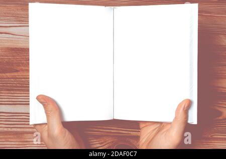 Men's hands holding open book with blank cover on light background Stock Photo