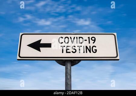 COVID-19 testing road sign, arrow on blue sky background. One way blank road sign with copy space. Arrow on a pole pointing in one direction. Stock Photo