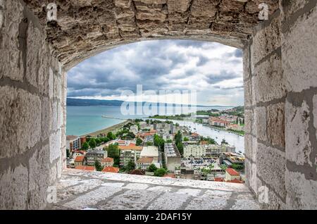 View from stone window of blue sea and red roofs in historic city center in Omis, Croatia