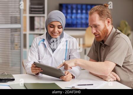 Female doctor showing medical prescription on digital tablet to her patient during his visit at hospital Stock Photo