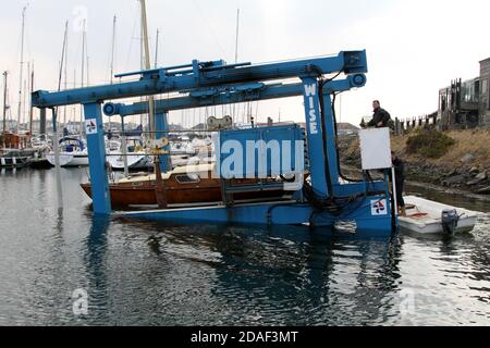 Troon Yacht Haven, Ayrshire , Scotland UK, Lowering boat into  the water via a crane boat lift hoist Stock Photo