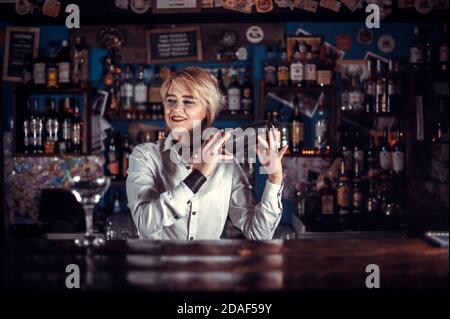 Focused woman tapster intensely finishes his creation in pub Stock Photo