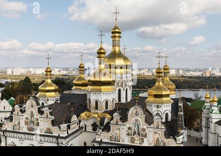 Kiev Pechersk Lavra. Cathedral of the Dormition. Kiev. Ukraine. Green and yellow autumn trees on background. Dnieper River and the panorama of Kiev in Stock Photo