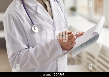Close-up of doctor in white coat filling medical card with pen at the hospital Stock Photo