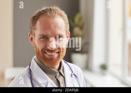 Close-up of bearded successful medical worker in white coat smiling at camera Stock Photo