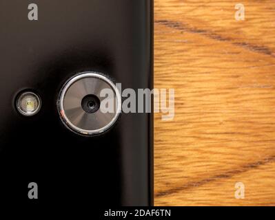 Closeup of a smart phone camera with lighting flash. On the right side of the photo empty background with wooden background. Stock Photo