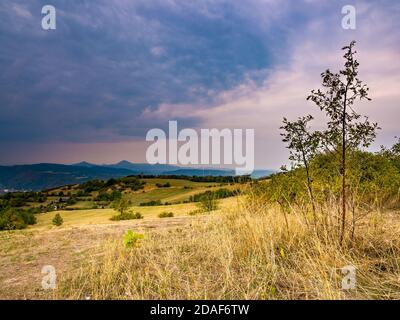 Dark heavy rain clouds coming over a hilly landscape Stock Photo