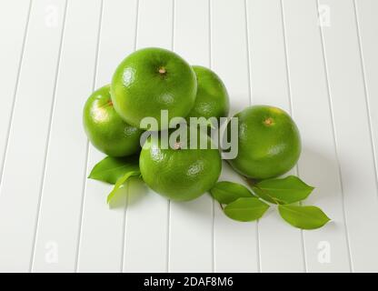 Five whole sweetie fruits (green grapefruits, pomelits) and leaves Stock Photo