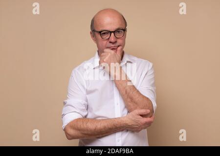 Senior man scratching his chin making a hard decision Stock Photo