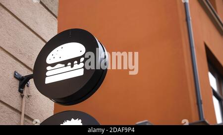 Circle black burger sign on wall behind glass Stock Photo
