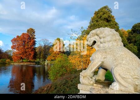 Chinese Guardian Lion statue overlooking the Palm House Pond with Autumn colour trees Kew Gardens Stock Photo