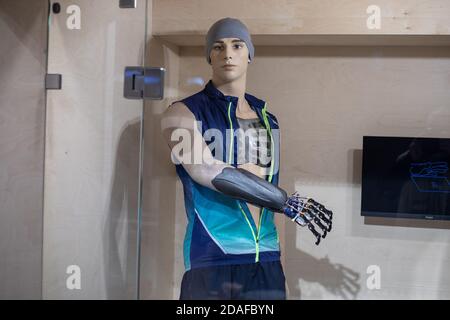 A mannequin in the form of a young man in sportswear with a prosthetic arm behind glass. Demonstration of new technologies in prosthetics. Robotic Stock Photo