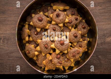 Star shaped christmas cookies with a hazelnut are lying in a cookie tin. Photographed from above. Stock Photo