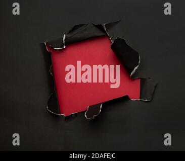 Black torn paper on red background. Black Friday campaign. Stock Photo