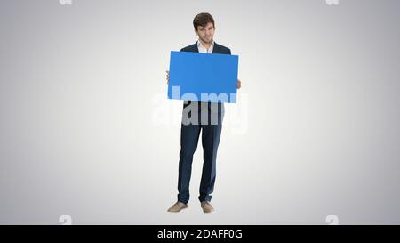 Young businessman holding blank sign looking at camera on gradie Stock Photo