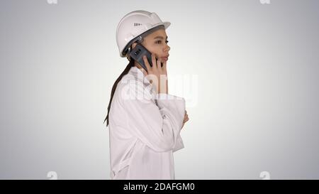 Female science engineer making a call while walking on gradient Stock Photo