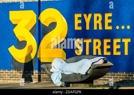 Pedestrian walking past a man sleeping rough on day 4 of the lockdown. Stock Photo