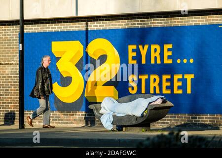 Pedestrian walking past a man sleeping rough on day 4 of the lockdown. Stock Photo