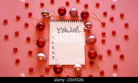 Notebook on pink background with christmas balls - new year wish list. Top view Stock Photo