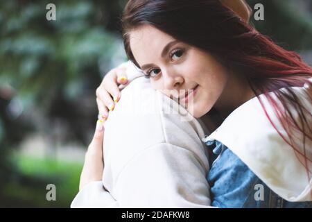 A beautiful girl embraces a young man with tenderness. Young happy couple in love on a walk. Loving couple.  Stock Photo