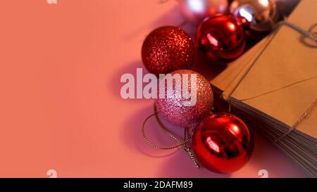Stack of letters from craft paper with christmas red and pink balls on pink background Stock Photo
