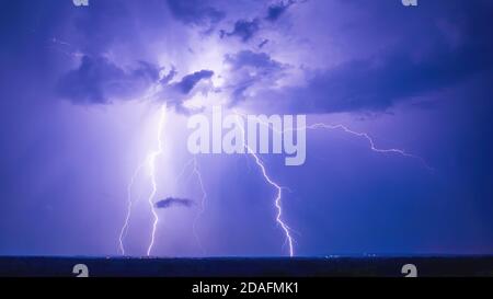 Strokes of cloud-to-ground lightning during grandiose night thunderstorm Stock Photo