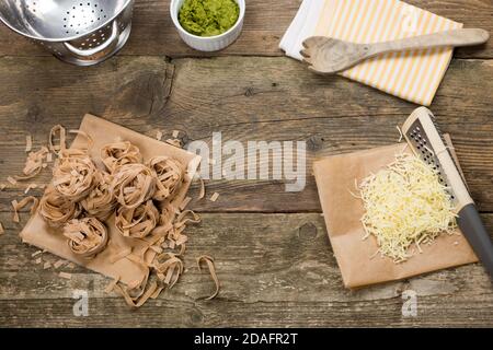 Wholegrain pasta tagliatelle type prepared for cooking. Cheese, wild garlic and walnut homemade pesto. Served on wooden table in vintage style Stock Photo