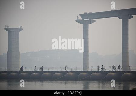 Varanasi, India, December 2015. People crossing a temporary bridge on the Ganges River, with the new one under construction in the background. Stock Photo