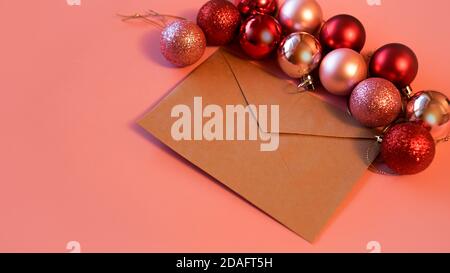 Envelope from craft paper with christmas red and pink balls on pink festive background with copy space Stock Photo