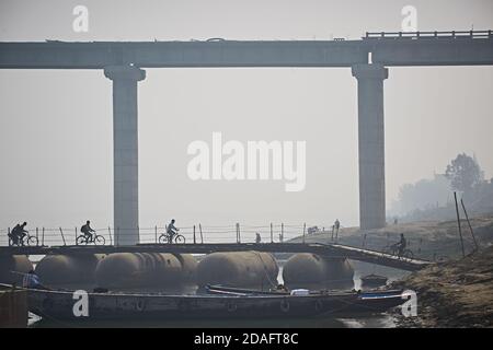 Varanasi, India, December 2015. People crossing a temporary bridge on the Ganges River, with the new one under construction in the background. Stock Photo