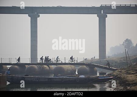 Varanasi, India, December 2015. People crossing a temporary bridge on the Ganges River, with the new one under construction in the background. Stock Photo