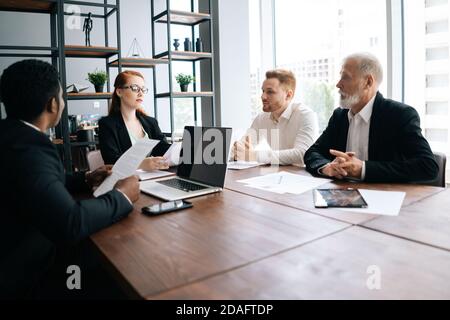 Motivated business woman leader holds meeting with employees at office desk Stock Photo