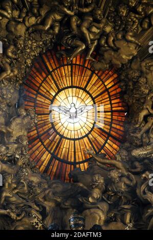 artistic stained glass window of the Holy Spirit depicted with a dove inside the basilica of San Pietro in Rome Stock Photo