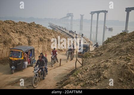 Varanasi, India, December 2015. People crossing a temporary bridge on the Ganges River, with the new one under construction in the background. Stock Photo