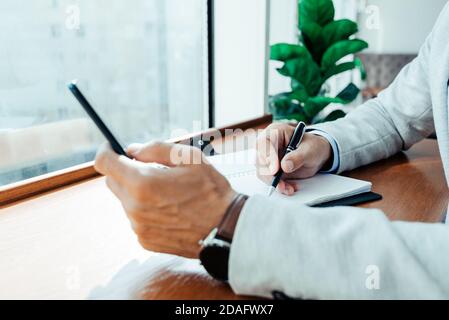 online training a student writes the text of a lecture from their phone to a Notepad. the businessman checks the schedule Stock Photo