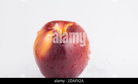A drop of water flows down a fresh juicy peach. Fresh organic Peach covered with dew drops. Fresh juicy peaches on a white plate. Stock Photo
