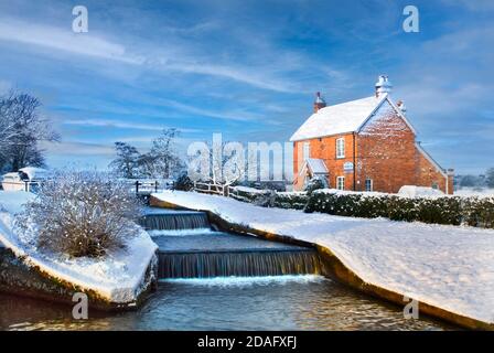 COTTAGE SNOW River Wey in winter with Lock-keepers cottage at Papercourt Lock at dawn sunrise on a picturesque landscape snowy winters day Surrey UK Stock Photo