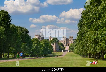 Windsor Castle in summer sun viewed down the Long Walk with people jogging and enjoying the view in warm vacation environment Windsor Berkshire UK